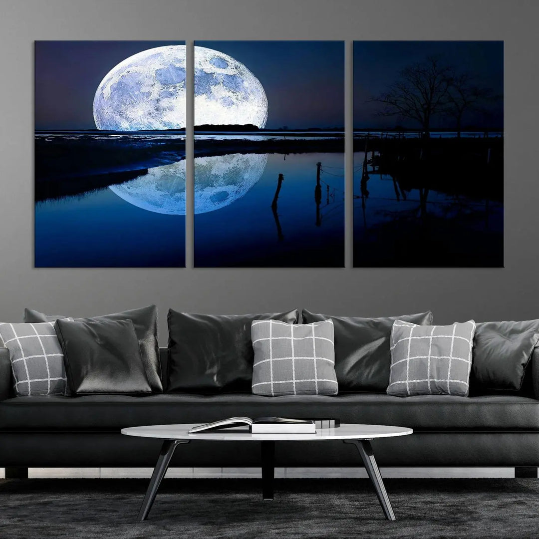 A mesmerizing Blue Moon Wall Art Canvas Print, depicting a lake landscape with a silhouetted tree, is beautifully presented on museum-quality canvas. This gallery-wrapped artwork, protected by a UV-coating to preserve its stunning details, stands out as an exquisite piece in the room.