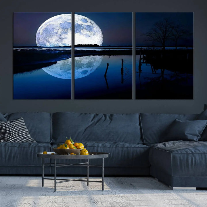 A mesmerizing Blue Moon Wall Art Canvas Print, depicting a lake landscape with a silhouetted tree, is beautifully presented on museum-quality canvas. This gallery-wrapped artwork, protected by a UV-coating to preserve its stunning details, stands out as an exquisite piece in the room.