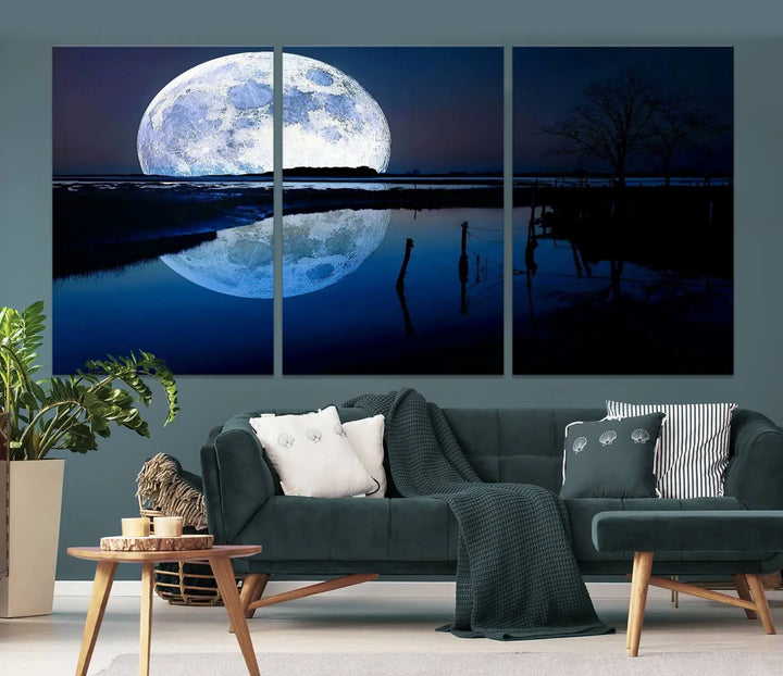 A mesmerizing Blue Moon Wall Art Canvas Print, depicting a lake landscape with a silhouetted tree, is beautifully presented on museum-quality canvas. This gallery-wrapped artwork, protected by a UV-coating to preserve its stunning details, stands out as an exquisite piece in the room.