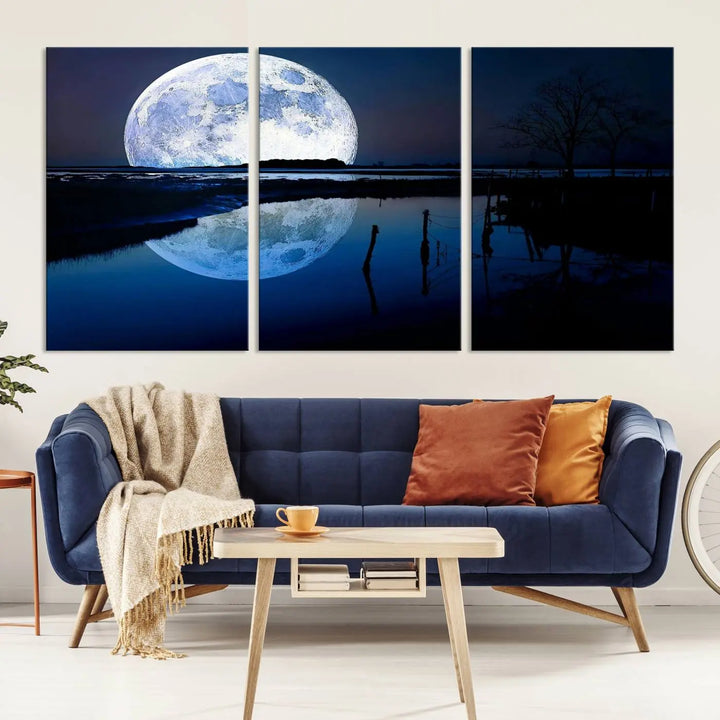 A mesmerizing Blue Moon Wall Art Canvas Print, depicting a lake landscape with a silhouetted tree, is beautifully presented on museum-quality canvas. This gallery-wrapped artwork, protected by a UV-coating to preserve its stunning details, stands out as an exquisite piece in the room.