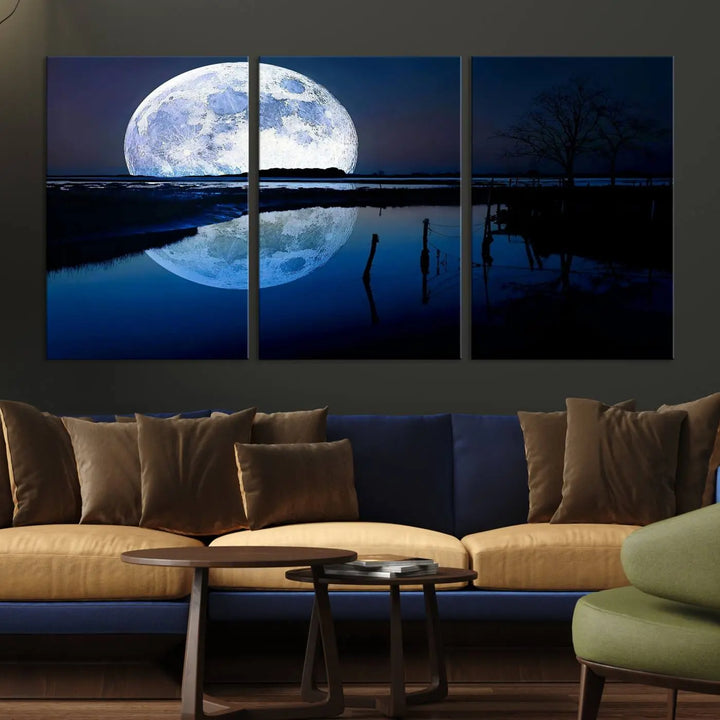 A mesmerizing Blue Moon Wall Art Canvas Print, depicting a lake landscape with a silhouetted tree, is beautifully presented on museum-quality canvas. This gallery-wrapped artwork, protected by a UV-coating to preserve its stunning details, stands out as an exquisite piece in the room.