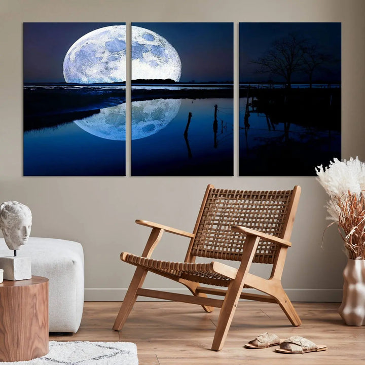 A mesmerizing Blue Moon Wall Art Canvas Print, depicting a lake landscape with a silhouetted tree, is beautifully presented on museum-quality canvas. This gallery-wrapped artwork, protected by a UV-coating to preserve its stunning details, stands out as an exquisite piece in the room.