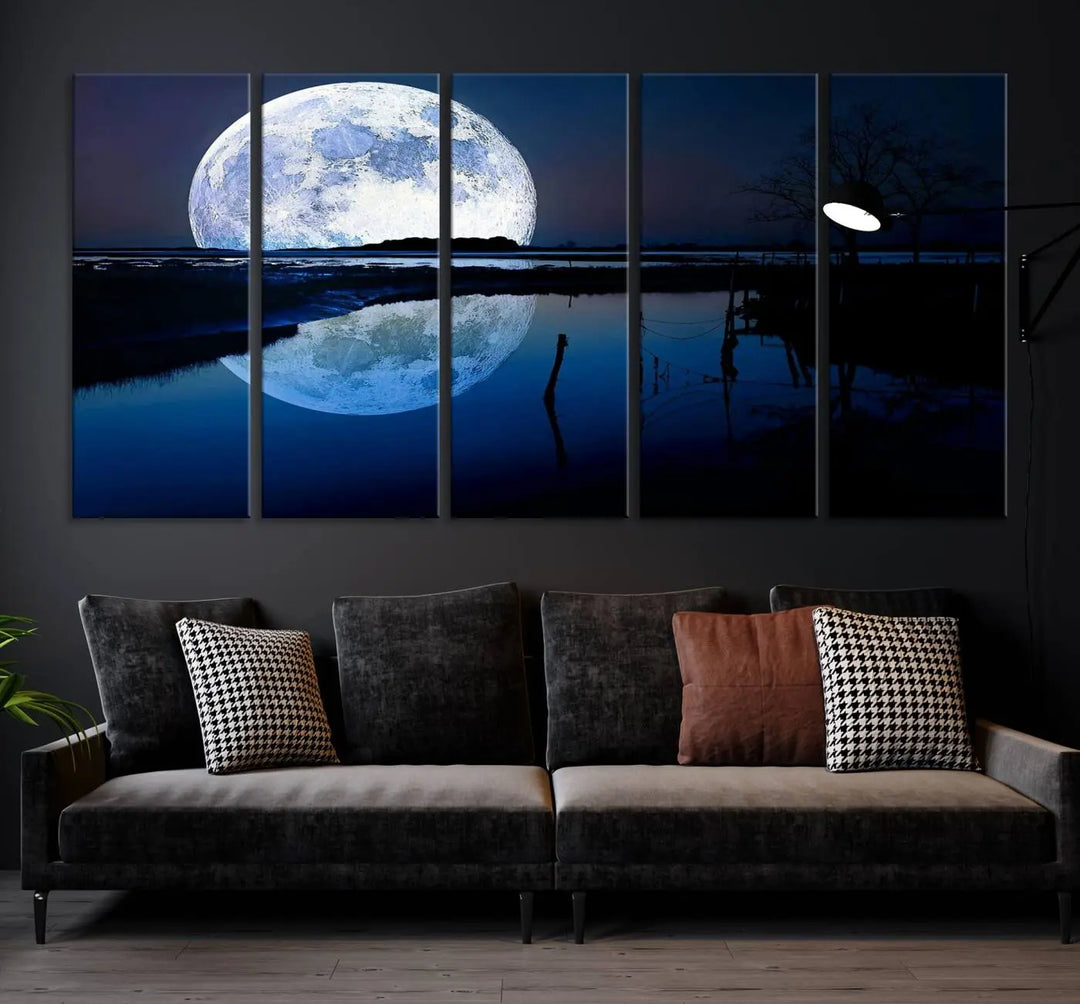 A mesmerizing Blue Moon Wall Art Canvas Print, depicting a lake landscape with a silhouetted tree, is beautifully presented on museum-quality canvas. This gallery-wrapped artwork, protected by a UV-coating to preserve its stunning details, stands out as an exquisite piece in the room.