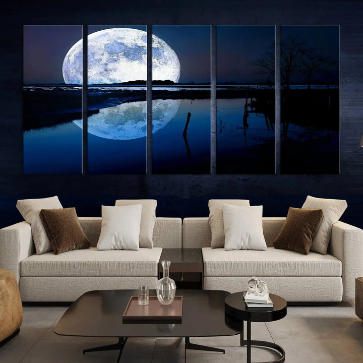 A mesmerizing Blue Moon Wall Art Canvas Print, depicting a lake landscape with a silhouetted tree, is beautifully presented on museum-quality canvas. This gallery-wrapped artwork, protected by a UV-coating to preserve its stunning details, stands out as an exquisite piece in the room.