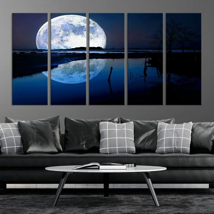 A mesmerizing Blue Moon Wall Art Canvas Print, depicting a lake landscape with a silhouetted tree, is beautifully presented on museum-quality canvas. This gallery-wrapped artwork, protected by a UV-coating to preserve its stunning details, stands out as an exquisite piece in the room.