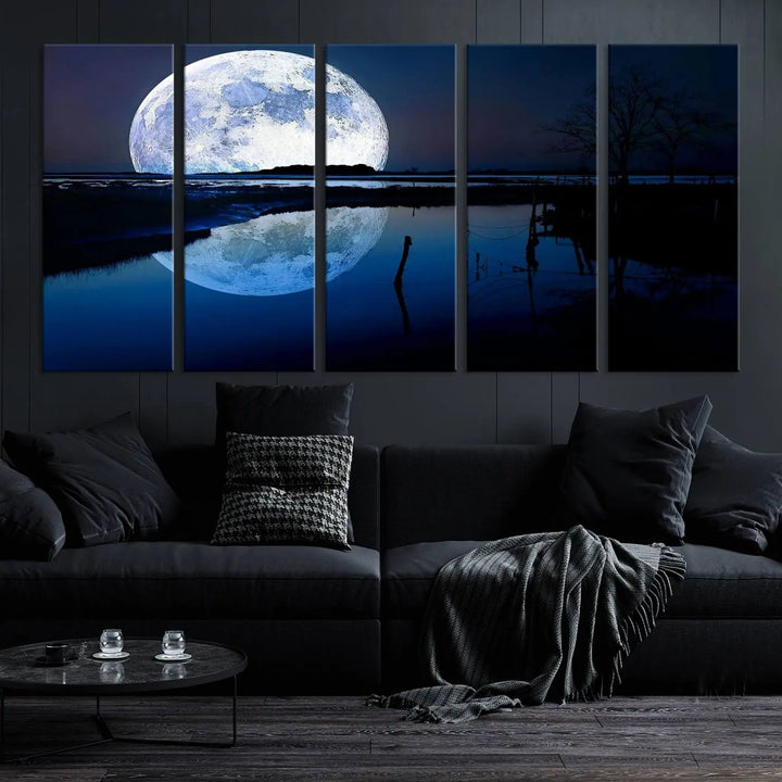 A mesmerizing Blue Moon Wall Art Canvas Print, depicting a lake landscape with a silhouetted tree, is beautifully presented on museum-quality canvas. This gallery-wrapped artwork, protected by a UV-coating to preserve its stunning details, stands out as an exquisite piece in the room.