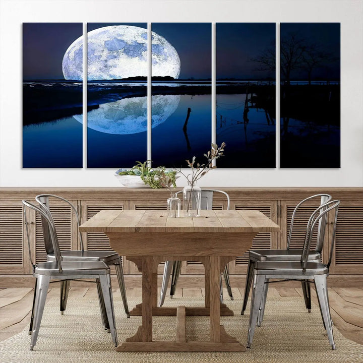 A mesmerizing Blue Moon Wall Art Canvas Print, depicting a lake landscape with a silhouetted tree, is beautifully presented on museum-quality canvas. This gallery-wrapped artwork, protected by a UV-coating to preserve its stunning details, stands out as an exquisite piece in the room.