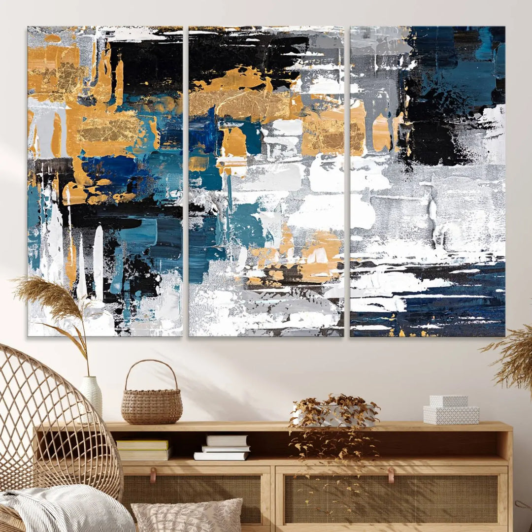 The Blue and Gold Abstract Canvas Wall Art – a triptych modern painting that's framed and ready to hang – features captivating brush strokes in blue, gold, black, and white to enhance the living room decor.