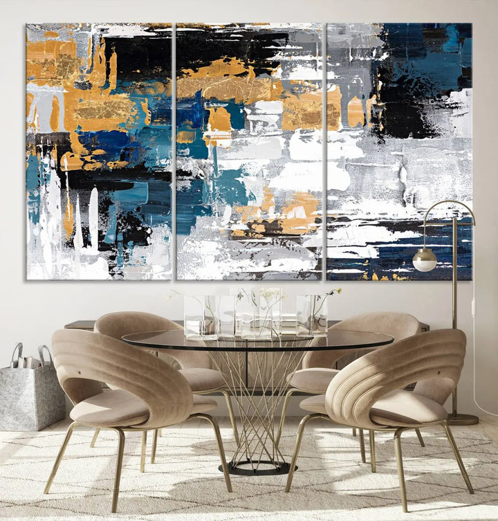 The Blue and Gold Abstract Canvas Wall Art – a triptych modern painting that's framed and ready to hang – features captivating brush strokes in blue, gold, black, and white to enhance the living room decor.