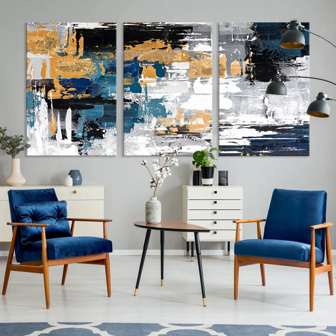 The Blue and Gold Abstract Canvas Wall Art – a triptych modern painting that's framed and ready to hang – features captivating brush strokes in blue, gold, black, and white to enhance the living room decor.