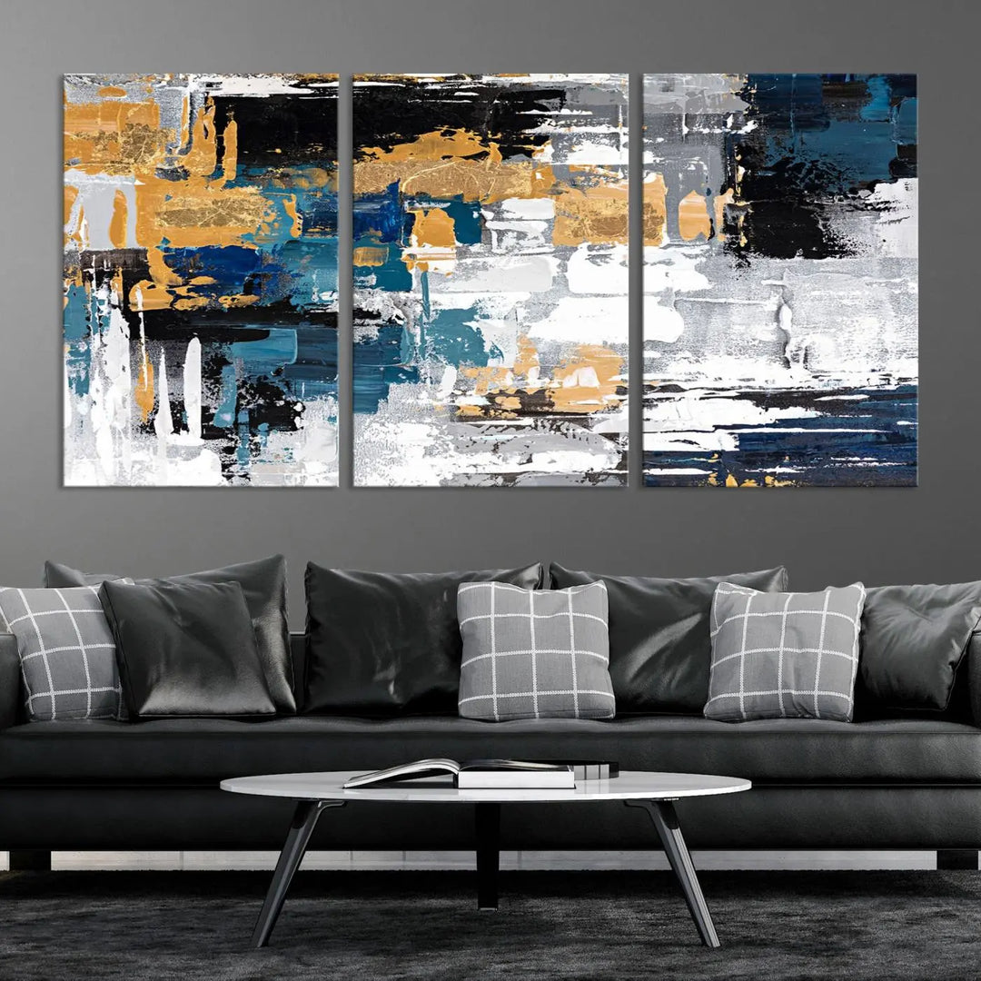 The Blue and Gold Abstract Canvas Wall Art – a triptych modern painting that's framed and ready to hang – features captivating brush strokes in blue, gold, black, and white to enhance the living room decor.