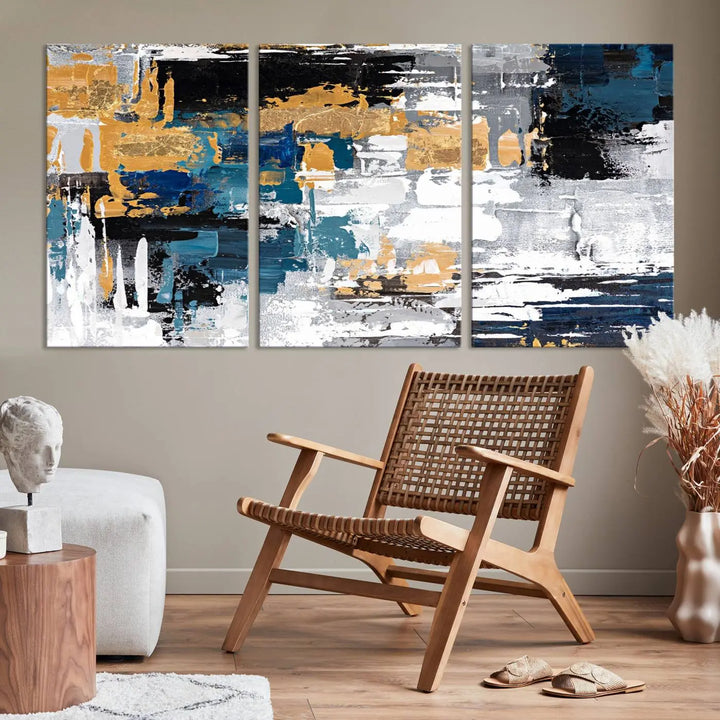 The Blue and Gold Abstract Canvas Wall Art – a triptych modern painting that's framed and ready to hang – features captivating brush strokes in blue, gold, black, and white to enhance the living room decor.