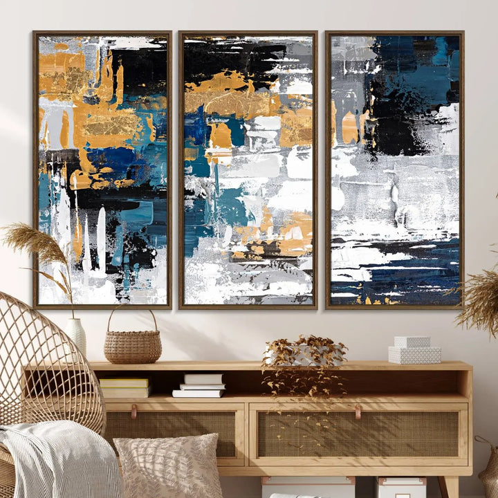 The Blue and Gold Abstract Canvas Wall Art – a triptych modern painting that's framed and ready to hang – features captivating brush strokes in blue, gold, black, and white to enhance the living room decor.