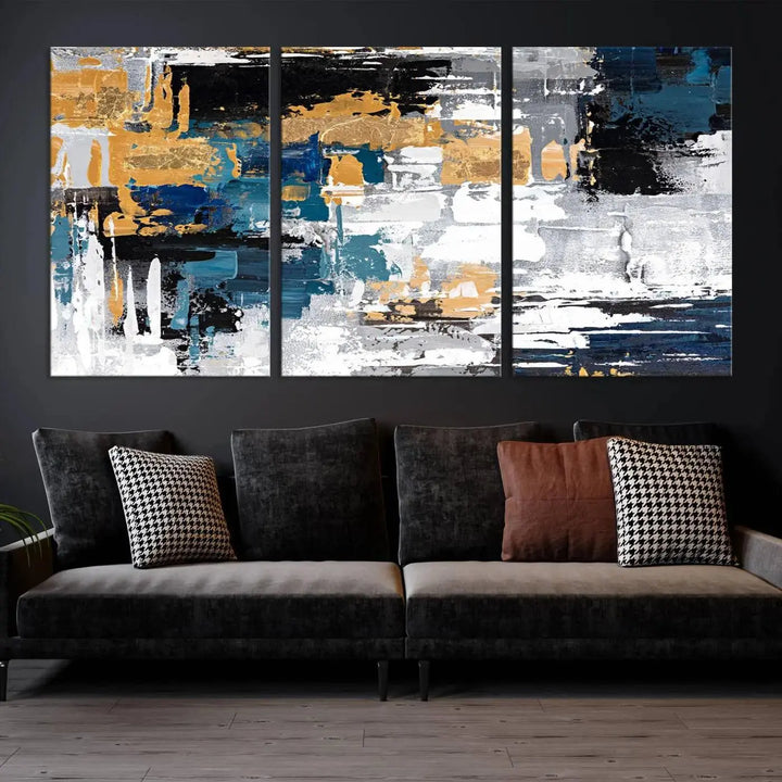 The Blue and Gold Abstract Canvas Wall Art – a triptych modern painting that's framed and ready to hang – features captivating brush strokes in blue, gold, black, and white to enhance the living room decor.