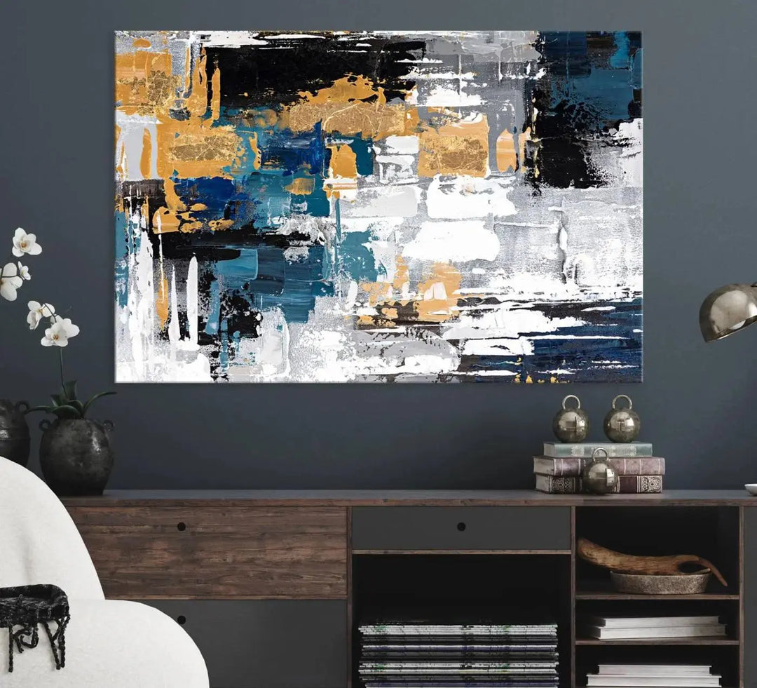 The Blue and Gold Abstract Canvas Wall Art – a triptych modern painting that's framed and ready to hang – features captivating brush strokes in blue, gold, black, and white to enhance the living room decor.