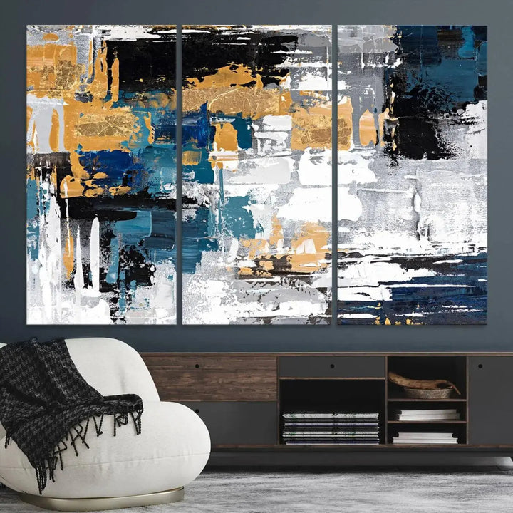 The Blue and Gold Abstract Canvas Wall Art – a triptych modern painting that's framed and ready to hang – features captivating brush strokes in blue, gold, black, and white to enhance the living room decor.