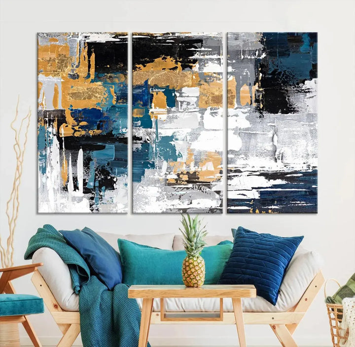 The Blue and Gold Abstract Canvas Wall Art – a triptych modern painting that's framed and ready to hang – features captivating brush strokes in blue, gold, black, and white to enhance the living room decor.