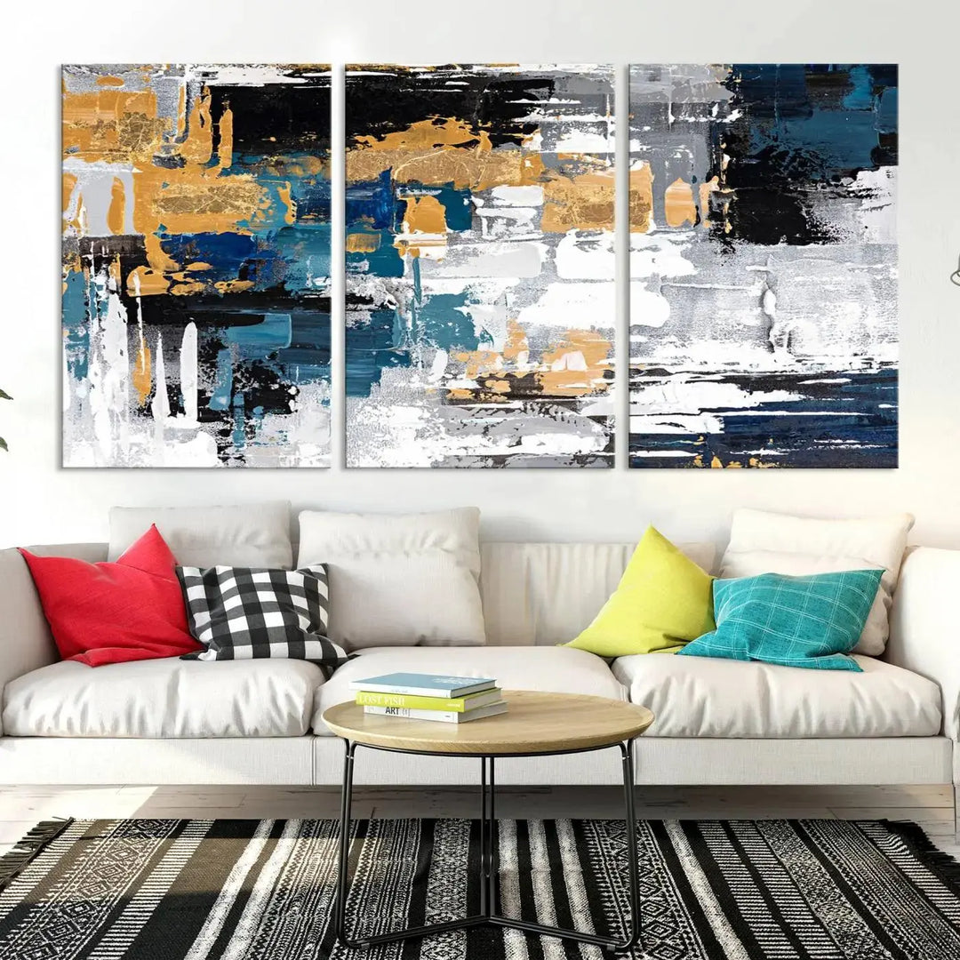 The Blue and Gold Abstract Canvas Wall Art – a triptych modern painting that's framed and ready to hang – features captivating brush strokes in blue, gold, black, and white to enhance the living room decor.