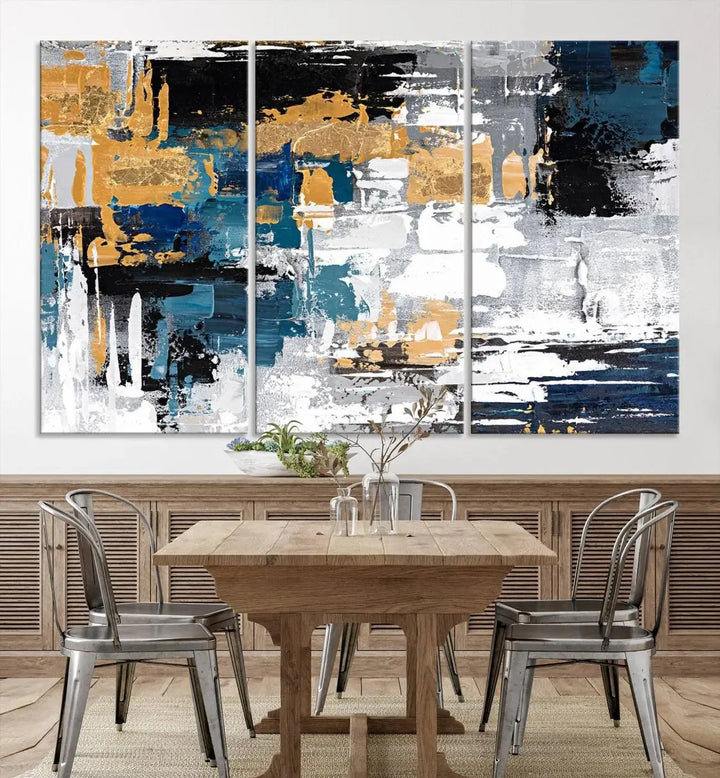 The Blue and Gold Abstract Canvas Wall Art – a triptych modern painting that's framed and ready to hang – features captivating brush strokes in blue, gold, black, and white to enhance the living room decor.