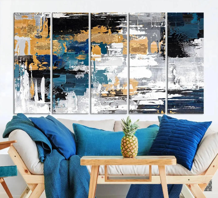 The Blue and Gold Abstract Canvas Wall Art – a triptych modern painting that's framed and ready to hang – features captivating brush strokes in blue, gold, black, and white to enhance the living room decor.