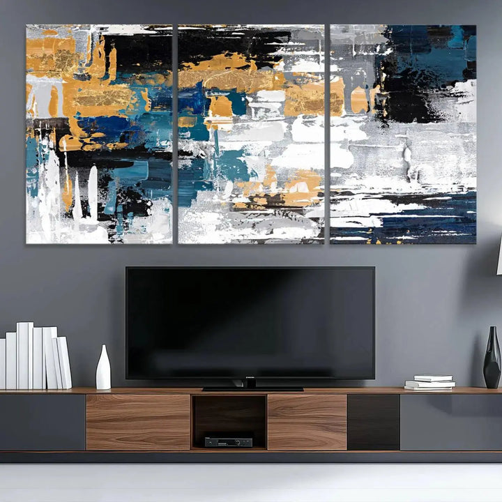 The Blue and Gold Abstract Canvas Wall Art – a triptych modern painting that's framed and ready to hang – features captivating brush strokes in blue, gold, black, and white to enhance the living room decor.