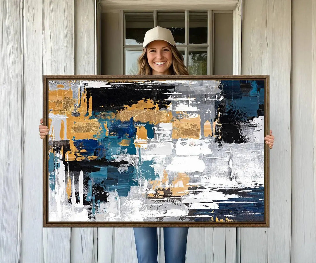 The Blue and Gold Abstract Canvas Wall Art – a triptych modern painting that's framed and ready to hang – features captivating brush strokes in blue, gold, black, and white to enhance the living room decor.