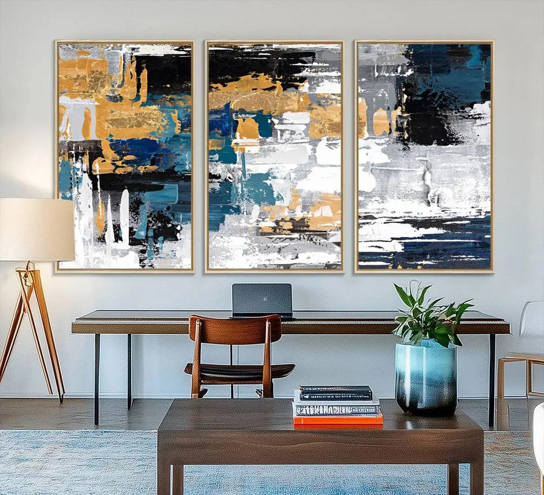 The Blue and Gold Abstract Canvas Wall Art – a triptych modern painting that's framed and ready to hang – features captivating brush strokes in blue, gold, black, and white to enhance the living room decor.