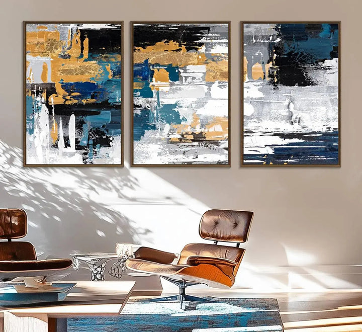 The Blue and Gold Abstract Canvas Wall Art – a triptych modern painting that's framed and ready to hang – features captivating brush strokes in blue, gold, black, and white to enhance the living room decor.