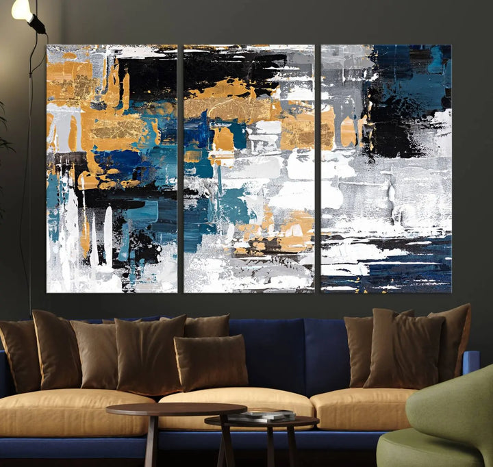 A sophisticated display of the Blue and Gold Abstract Canvas Wall Art – Triptych Modern Painting, featuring a captivating blend of blue, gold, black, and white tones, is elegantly framed and ready to hang.