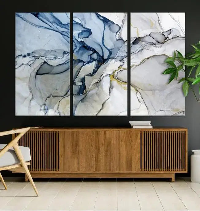 The "Blue and Gray Marble Fluid Effect Wall Art Abstract Canvas Wall Art Print" graces the dark wall, ready to hang. This triptych abstract art boasts a UV-protective coating for vibrant longevity in your space.