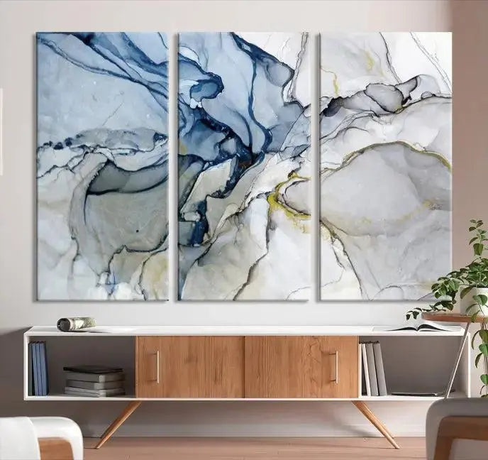 The "Blue and Gray Marble Fluid Effect Wall Art Abstract Canvas Wall Art Print" graces the dark wall, ready to hang. This triptych abstract art boasts a UV-protective coating for vibrant longevity in your space.