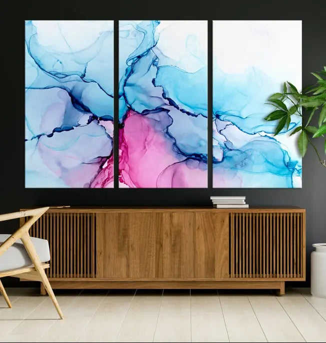 The "Blue and Pink Marble Fluid Effect Wall Art Abstract Canvas Wall Art Print" graces a dark wall. This exquisite piece is created on museum-quality polycotton canvas with a UV-protective coating.