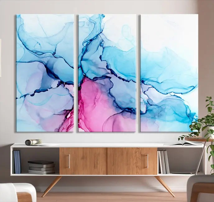 The "Blue and Pink Marble Fluid Effect Wall Art Abstract Canvas Wall Art Print" graces a dark wall. This exquisite piece is created on museum-quality polycotton canvas with a UV-protective coating.