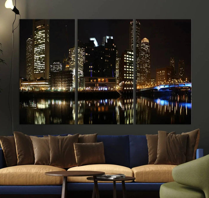 The Boston Night Skyline Cityscape View Wall Art Canvas Print depicts a triptych of the illuminated city reflected in water, enhancing a modern living room with its vibrant imagery. This gallery-wrapped masterpiece on museum-quality canvas brings an artistic flair to your space.