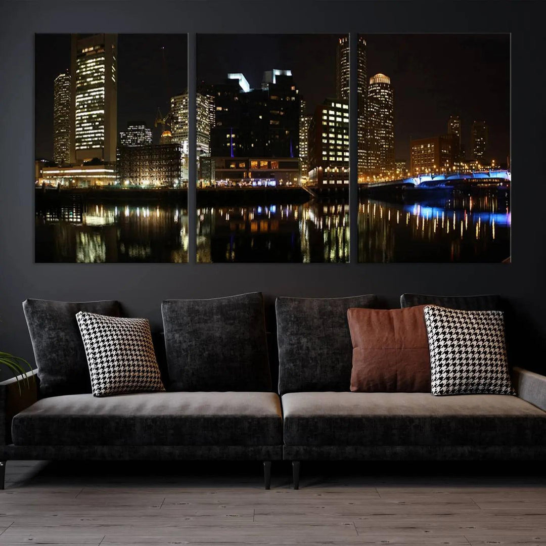 The Boston Night Skyline Cityscape View Wall Art Canvas Print depicts a triptych of the illuminated city reflected in water, enhancing a modern living room with its vibrant imagery. This gallery-wrapped masterpiece on museum-quality canvas brings an artistic flair to your space.