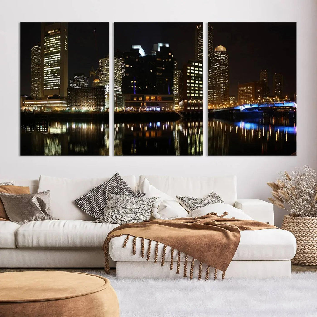 The Boston Night Skyline Cityscape View Wall Art Canvas Print depicts a triptych of the illuminated city reflected in water, enhancing a modern living room with its vibrant imagery. This gallery-wrapped masterpiece on museum-quality canvas brings an artistic flair to your space.