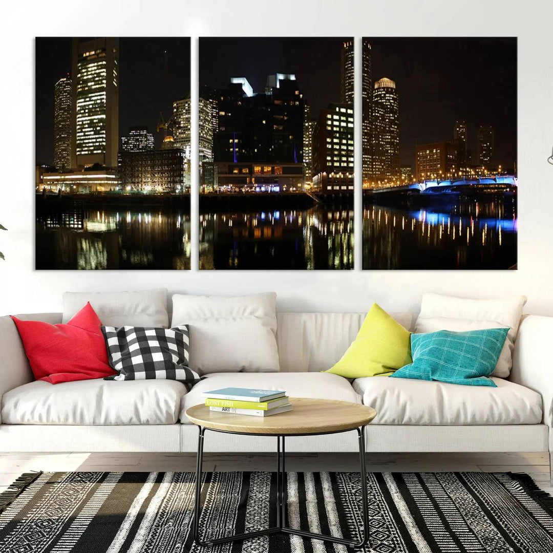 The Boston Night Skyline Cityscape View Wall Art Canvas Print depicts a triptych of the illuminated city reflected in water, enhancing a modern living room with its vibrant imagery. This gallery-wrapped masterpiece on museum-quality canvas brings an artistic flair to your space.