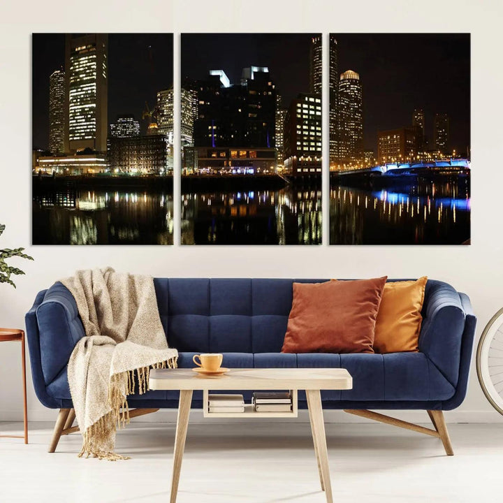 The Boston Night Skyline Cityscape View Wall Art Canvas Print depicts a triptych of the illuminated city reflected in water, enhancing a modern living room with its vibrant imagery. This gallery-wrapped masterpiece on museum-quality canvas brings an artistic flair to your space.