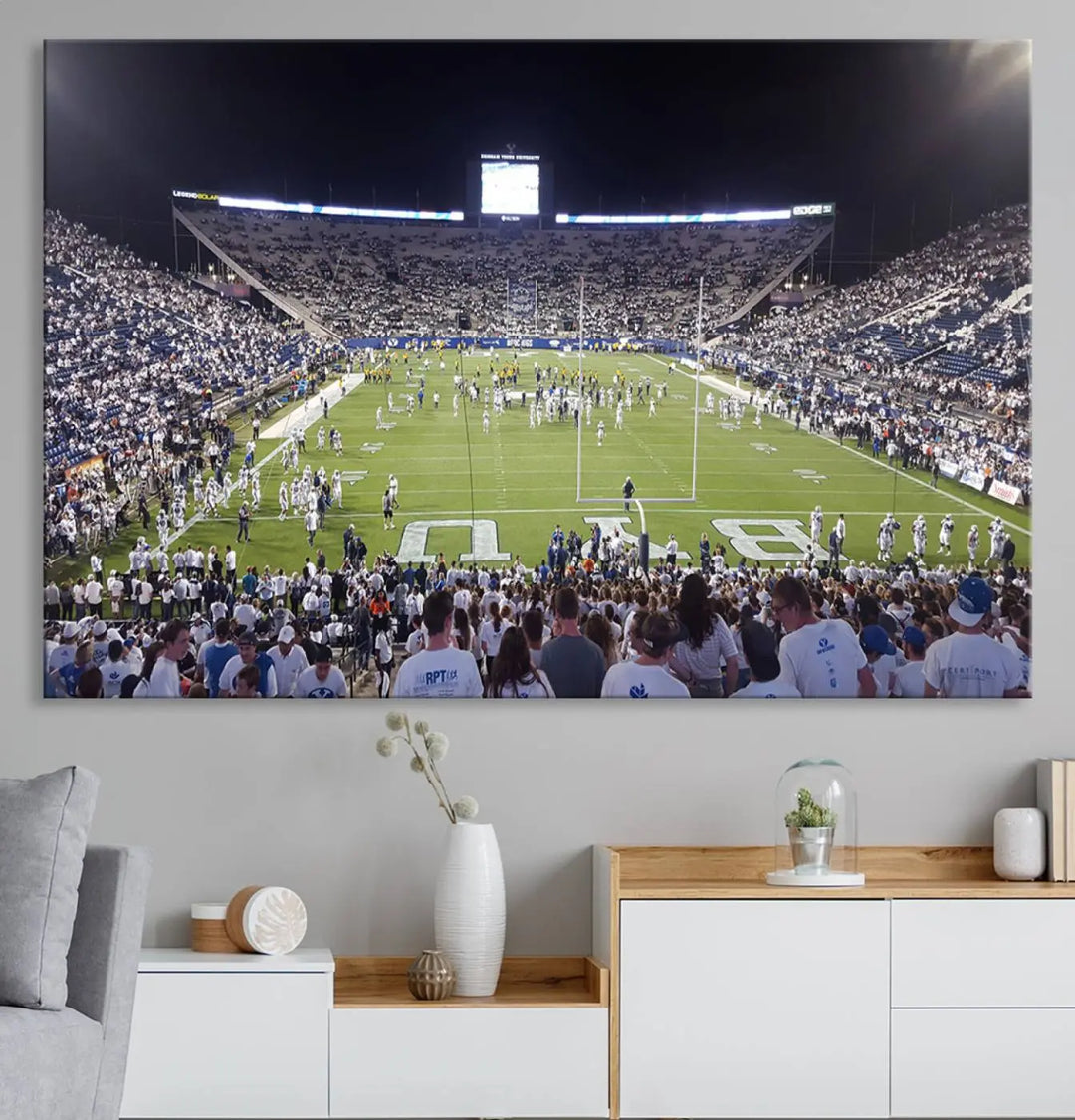 The living room is enhanced by a stunning triptych featuring the Brigham Young University Cougars Football Team Print. This premium canvas captures the vibrant atmosphere of Provo's LaVell Edwards Stadium at night, vividly portraying spectators and players on a well-lit field to bring an electrifying ambiance into your home.