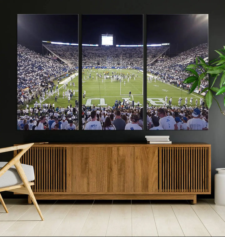 The living room is enhanced by a stunning triptych featuring the Brigham Young University Cougars Football Team Print. This premium canvas captures the vibrant atmosphere of Provo's LaVell Edwards Stadium at night, vividly portraying spectators and players on a well-lit field to bring an electrifying ambiance into your home.