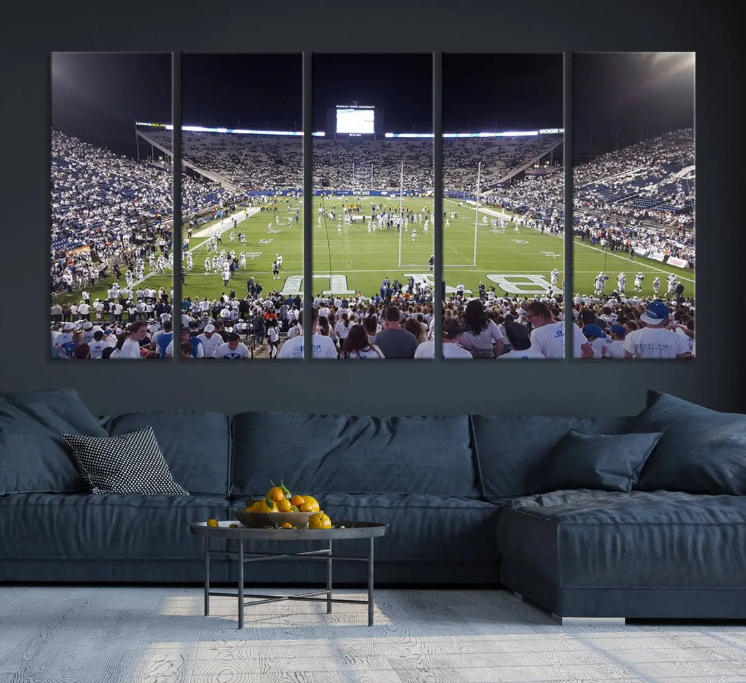 The living room is enhanced by a stunning triptych featuring the Brigham Young University Cougars Football Team Print. This premium canvas captures the vibrant atmosphere of Provo's LaVell Edwards Stadium at night, vividly portraying spectators and players on a well-lit field to bring an electrifying ambiance into your home.