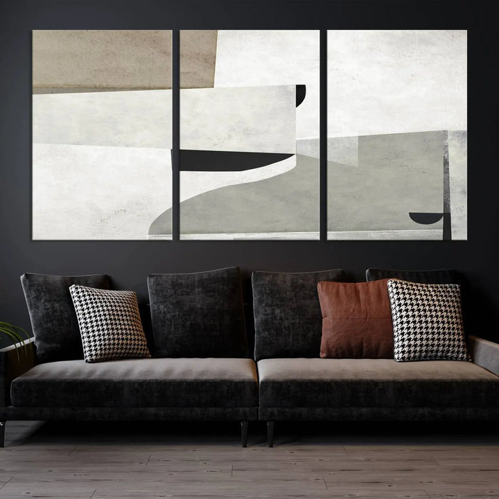 The Brown Gray Figures Abstract Wall Art Canvas Print is displayed as a triptych on a dark wall. The piece is gallery wrapped, offering a seamless finish and enhanced durability due to its UV-protective coating.