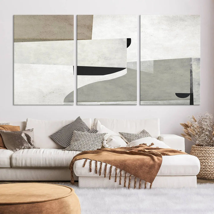 The Brown Gray Figures Abstract Wall Art Canvas Print is displayed as a triptych on a dark wall. The piece is gallery wrapped, offering a seamless finish and enhanced durability due to its UV-protective coating.