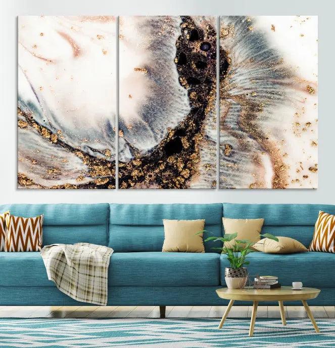 The Brown Marble Fluid Effect Wall Art Abstract Canvas Wall Art Print, with its mesmerizing black, white, and gold swirls, brings an exquisite touch to the space. This museum-quality canvas is elegantly displayed in a modern living room setting.