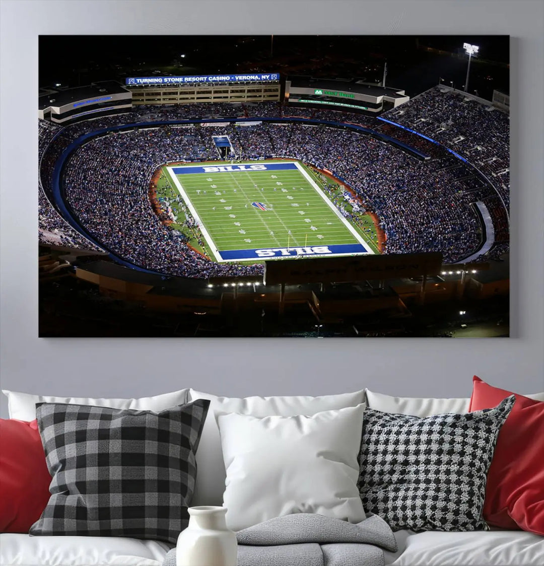 Above the couch hangs a museum-quality triptych featuring the Buffalo Bills NFL Football Team: a stunning canvas print of Highmark Stadium packed with enthusiastic spectators at night. The high-resolution printing technique captures every detail to perfection, making it ready to hang and instantly elevate any space.