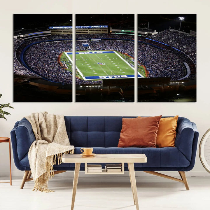 Above the couch hangs a museum-quality triptych featuring the Buffalo Bills NFL Football Team: a stunning canvas print of Highmark Stadium packed with enthusiastic spectators at night. The high-resolution printing technique captures every detail to perfection, making it ready to hang and instantly elevate any space.