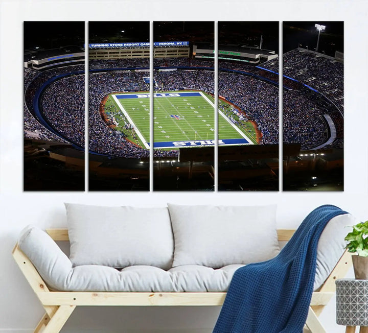 Above the couch hangs a museum-quality triptych featuring the Buffalo Bills NFL Football Team: a stunning canvas print of Highmark Stadium packed with enthusiastic spectators at night. The high-resolution printing technique captures every detail to perfection, making it ready to hang and instantly elevate any space.