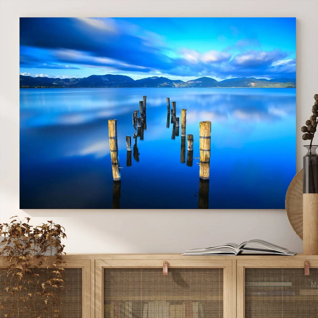 The Calm Waters Lake Canvas Art, featuring a tranquil pier reflection set against a mountainous backdrop, showcases its elegance with a gallery wrap and Canon print quality.