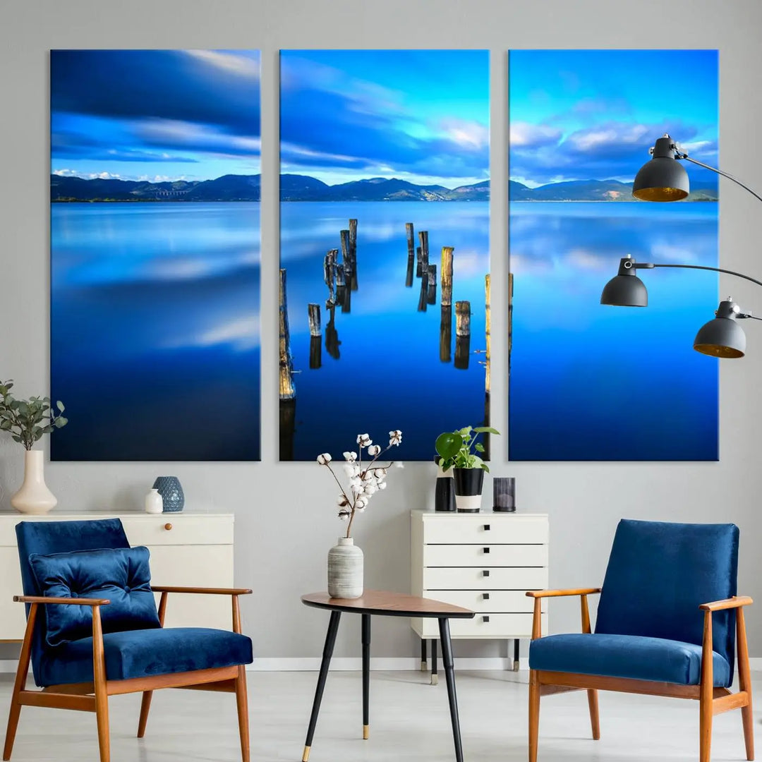 The Calm Waters Lake Canvas Art, featuring a tranquil pier reflection set against a mountainous backdrop, showcases its elegance with a gallery wrap and Canon print quality.