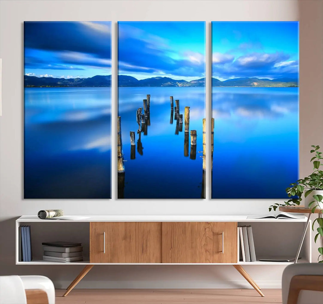 The Calm Waters Lake Canvas Art, featuring a tranquil pier reflection set against a mountainous backdrop, showcases its elegance with a gallery wrap and Canon print quality.